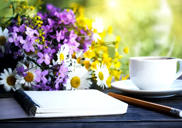 Cuaderno blanco en blanco, flores y taza de café en el escritorio — Foto de Stock