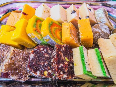 Canlı Hint tatlı geleneğini, çeşitli, renkli ve zarif bir tabakta sunulan zengin dokulu karışık şekerlerin büyüleyici bir fotoğrafıyla yakalayın..