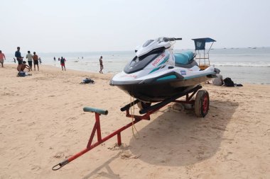 6 Aralık 2025, Panaji, Goa, Hindistan - Beyaz ve deniz mavisi bir jet ski kumlu bir tropik plajda kırmızı bir römorkta oturuyor.