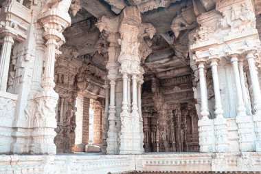 Hampi 'deki entrika oymalı taş sütunlar mitolojik figürler ve Vijayanagara dönemine ait detaylı yardım çalışmaları sergiliyor. Bu mimari başyapıt antik zanaatkarlığı, ruhani sembolizmi ve tapınak sanatını yansıtıyor..