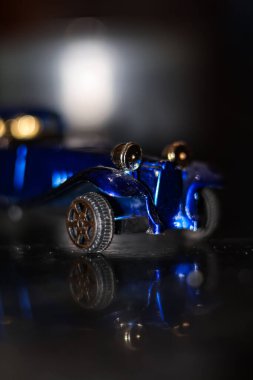 Kalın bir beyaz zemin sisi tabakasından çıkan klasik siyah bir oyuncak arabanın yan görüntüsü.