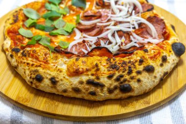 Salamlı, soğanlı, domatesli ve taze fesleğenli Napoli pizzası.