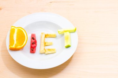 ahşap bir masa üzerinde farklı meyve kelime diyet ile beyaz plaka