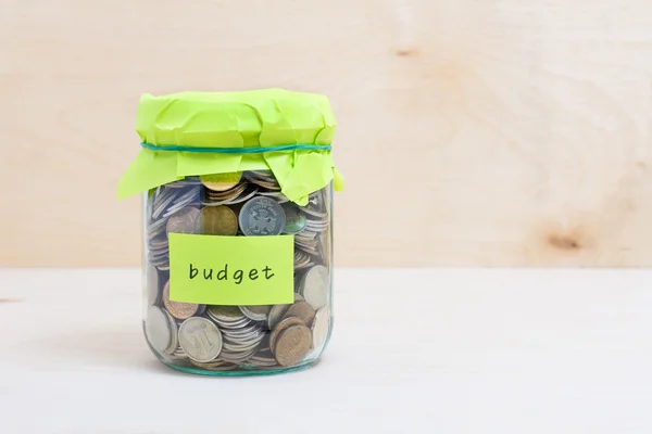 Financial concept. Coins in glass money jar with budget label. Wooden background — Stock Photo, Image