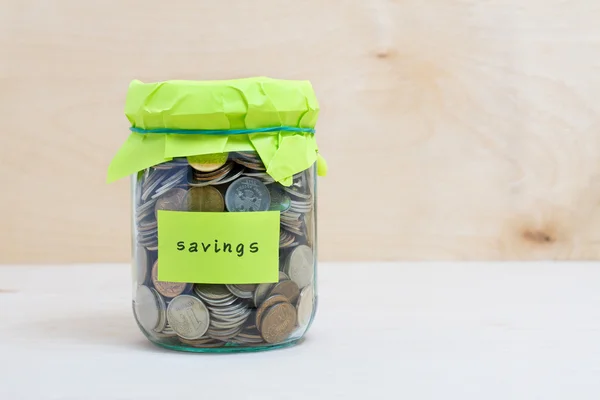 Financial concept. Coins in glass money jar with savings label. Wooden background — Stock Photo, Image