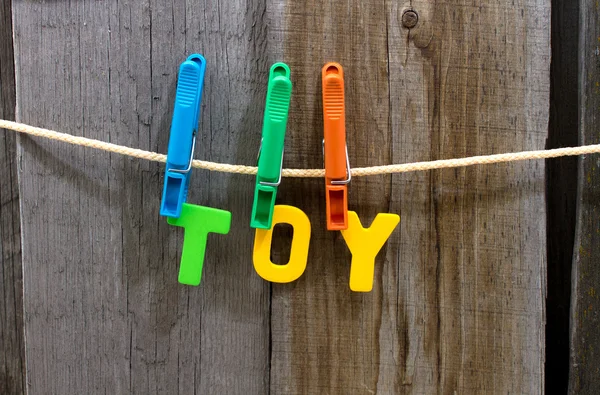 Parola giocattolo fissare mollette su una corda dietro uno sfondo di legno — Foto Stock