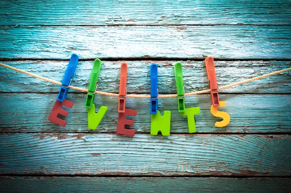 ahşap arka plan arkasında bir ip üzerinde clothespins kelime olaylarını tutturmak