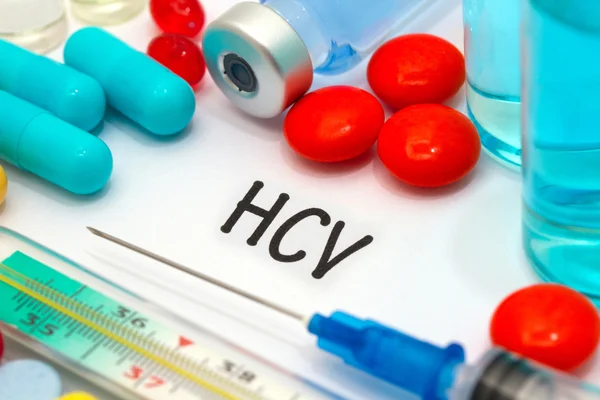 HCV - діагноз, написаний на білому аркуші паперу. Шприц і вакцина проти наркотиків — стокове фото