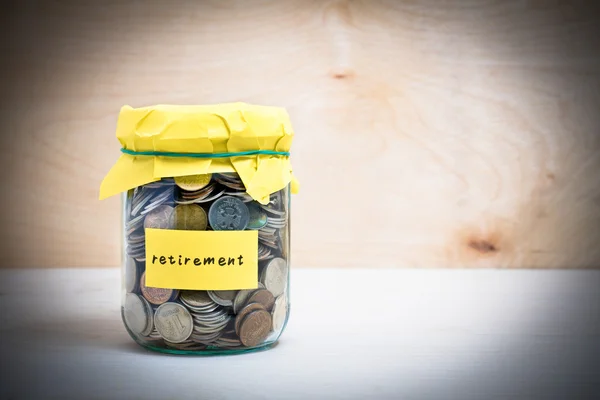 Financial concept. Coins in glass money jar with retirement label. Wooden background — Stock Photo, Image