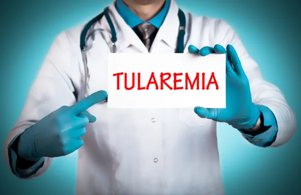 O doutor guarda um cartão com o nome do diagnóstico - tularemia — Fotografia de Stock