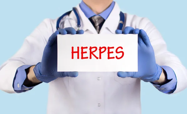 O doutor guarda um cartão com o nome do diagnóstico - herpes — Fotografia de Stock