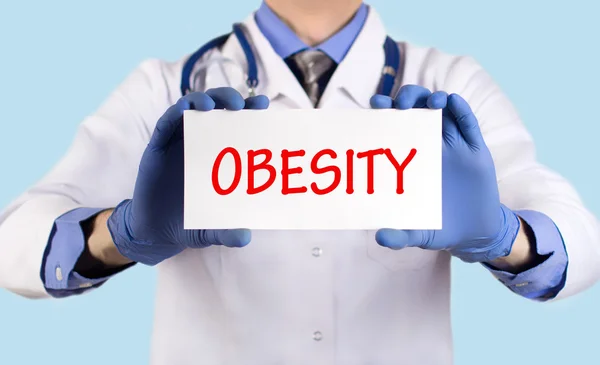 Лікар тримає карту з назвою діагнозу - ожиріння — стокове фото