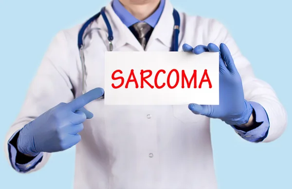El médico guarda una tarjeta con el nombre del diagnóstico - sarcoma — Foto de Stock