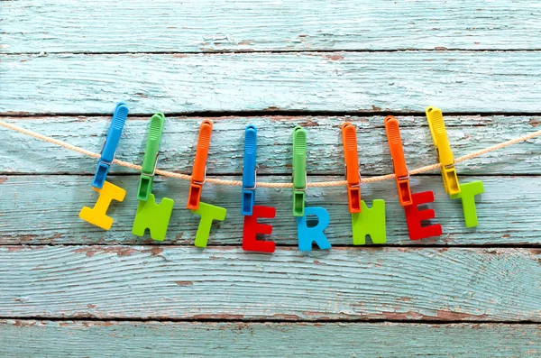 Internet Word Fast wasknijpers aan een touw achter een houten achtergrond — Stockfoto