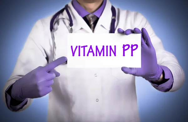 El doctor guarda una tarjeta con el nombre de la vitamina PP — Foto de Stock