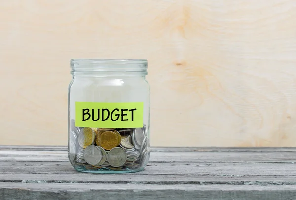 Label on a glass jar with the inscription - budget. Glass jar with coins. Financial concept on wooden background — Stock Photo, Image