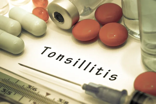 Тонзиллит - диагноз, написанный на белом листе бумаги. Шприц и вакцина с лекарствами — стоковое фото