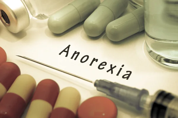 Анорексія - діагностика, написана на білому папері. Шприц і вакцини з наркотиками — стокове фото
