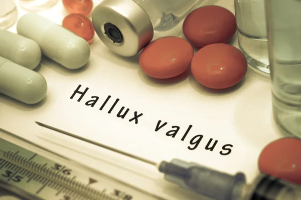 Hallux valgus - diagnóstico escrito en un papel blanco. Jeringa y vacuna con medicamentos — Foto de Stock