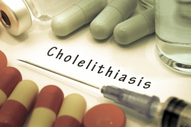 Cholelithiasis - beyaz bir kağıt parçası üzerinde yazılı tanı. Şırınga ve uyuşturucu ile aşı.
