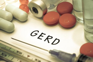 GERD - diagnosis written on a white piece of paper. Syringe and vaccine with drugs clipart