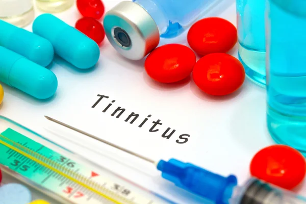 Tinnitus - diagnóstico escrito en un pedazo de papel blanco. Jeringa y vacuna con medicamentos . — Foto de Stock