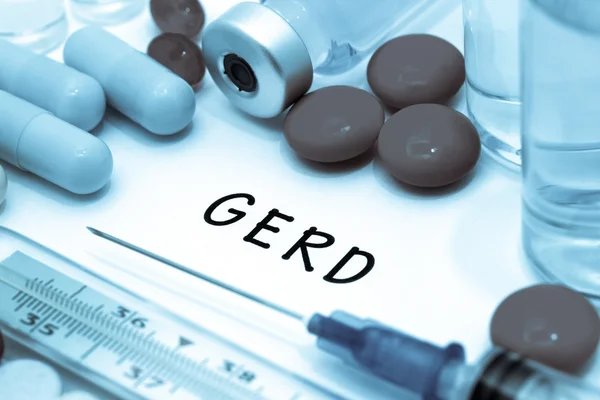 GERD - диагноз, написанный на белом листе бумаги. Шприц и вакцина с лекарствами — стоковое фото