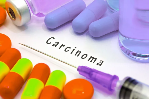 Carcinoma: diagnóstico escrito en un papel blanco. Jeringa y vacuna con medicamentos . — Foto de Stock