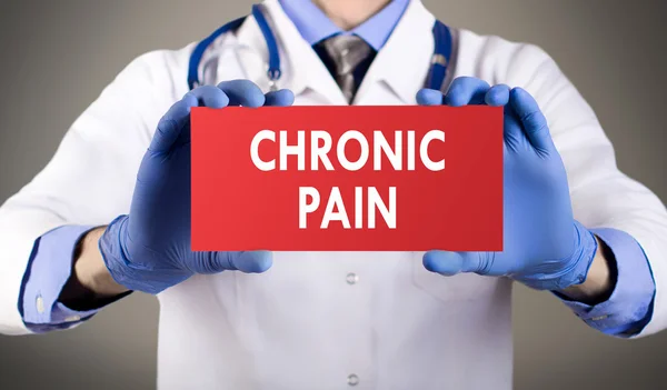 Las manos del doctor con guantes azules muestran la palabra dolor crónico. Concepto médico . —  Fotos de Stock