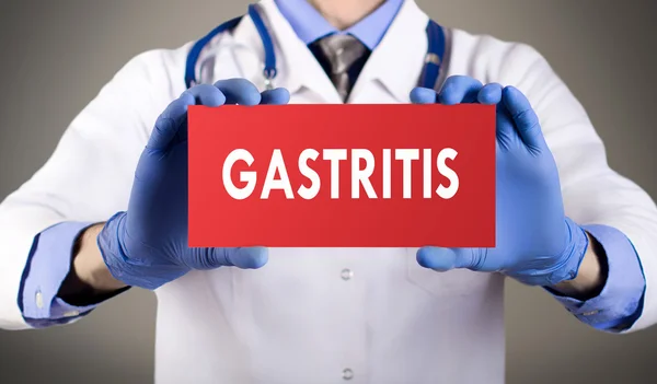 Arzthände in blauen Handschuhen zeigen das Wort Gastritis. medizinisches Konzept. — Stockfoto