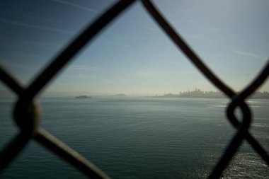 Alcatraz Adası ve San Francisco şehir silueti körfezin karşısındaki tel örgülerden görülebiliyor. Bu da kaçış ve sınırlama temalarını gösteriyor.