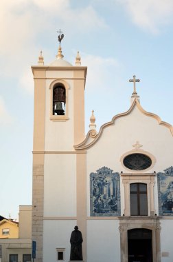 Sıcak akşam ışığı Portekiz 'in Aveiro kentindeki Igreja de Vera Cruz' da çan kulesini ve geleneksel mavi azulejo fayanslarını aydınlatıyor.