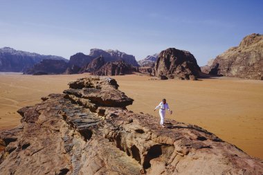 Ürdün 'ün Wadi Rum kentinin berrak mavi gökyüzü altındaki manzaralı çöl manzarasını keşfederken özgürlük ve macera hisseden kadın