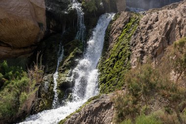 Bereketli yeşillikle kayalık arazide sakin bir şelale..