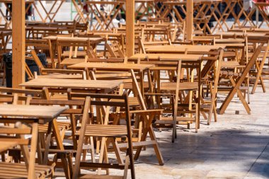 Güneşli bir günde boş masa ve sandalyelerle dolu açık hava ahşap kafeteryası..