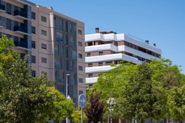 Modern şehir mimarisi: yemyeşil ve açık mavi gökyüzüne sahip çağdaş apartman kompleksi.