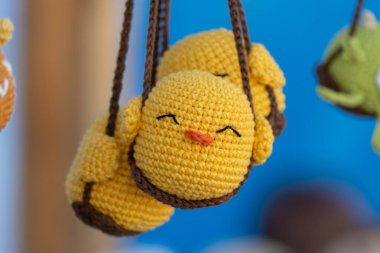 Adorable handmade yellow knit bird toys with smiling faces hanging on display.