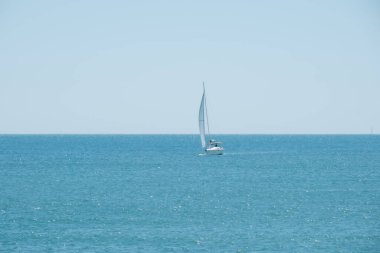 Durgun yelkenli berrak gökyüzünün altında kristal mavi denizde süzülüyor.