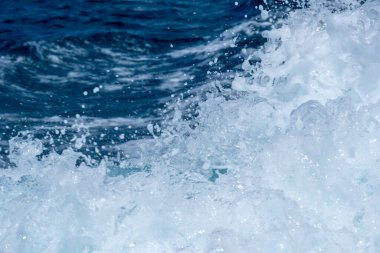 Dinamik okyanus dalgaları, mavi sularda köpüklü bir su sıçramasının ortasında yakalanır..