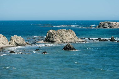 Turkuaz suları ve berrak mavi gökyüzü olan görkemli kıyı kayalıkları..