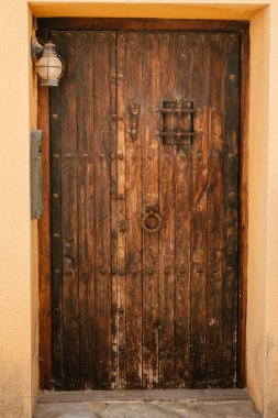 Metal detaylarla dolu ahşap bir kapı ve Akdeniz ayarlarında klasik bir fener..