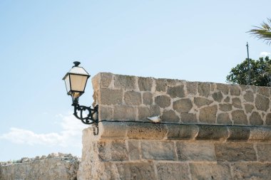 Gökyüzüne karşı tarihi taş duvar ve fener.