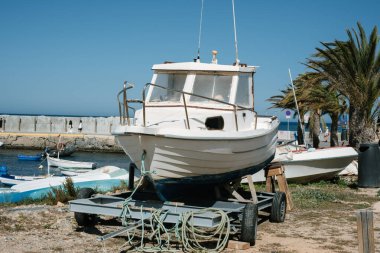 Güneşli sahil limanında palmiye ağaçlarıyla dolu bir karavanda eski bir tekne..