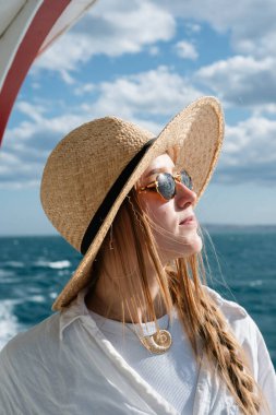 Hasır şapkalı kadın güneşli bir günde deniz melteminin tadını çıkarıyor..