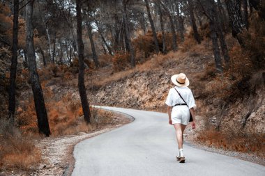 Sonbaharda dingin orman yolunda gezinen bir kadın.