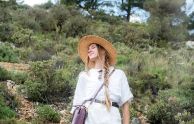 Hasır şapkalı kadın güneşli bir günde doğanın tadını çıkarıyor..