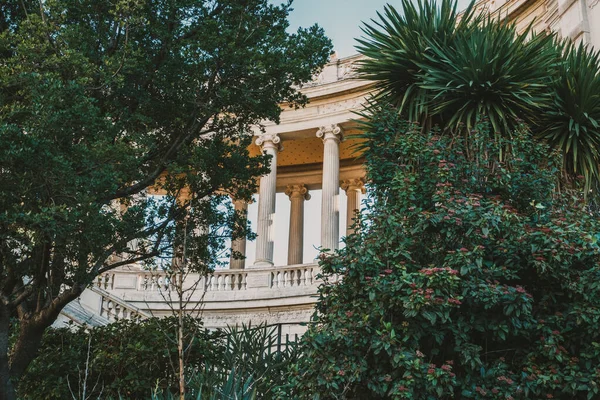 Tarihi mimari: güneşli şehir parkında yemyeşil ortamda klasik sütunlar.