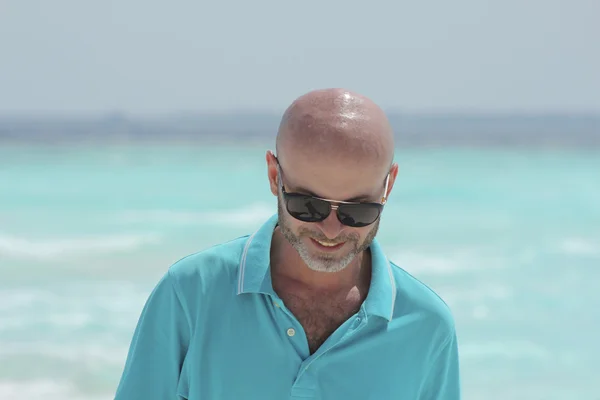 Hombre de mediana edad en la playa en camisa turquesa Imágenes De Stock Sin Royalties Gratis