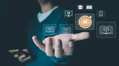 Bir kişi, eğitim, öğrenme ve hedeflere ulaşma ikonlarıyla sanal bir arayüze erişmek için akıllı telefon kullanır, gelecekte başarılı olmak için çevrimiçi kurslar ve beceri geliştirme kavramını temsil eder.