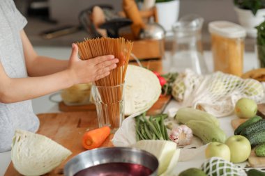 Çocuklar bardaktaki spagettiyi düzeltirken ellerini kapatıyorlar.